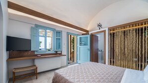 Een slaapkamer met een bed, een bankje, een televisie en een kledingkast.