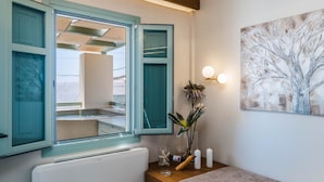 Een badkamer met smaragdgroene kastjes, een witte radiator, een houten wastafelmeubel, een wandlamp en een schilderij van een boom.