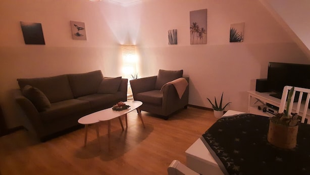 A living room with a sofa, armchairs, a coffee table, a TV, and a staircase. - Cozy 2 room apartment (List)