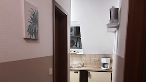 A narrow hallway leading to a kitchen with a sink, countertop, and a microwave. - Cozy 2 room apartment (List)