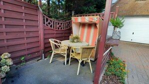 A patio with wicker furniture, a red gate, and a garage door. - Cozy 2 room apartment (List)