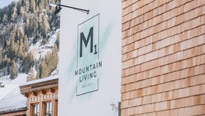 A building with a wooden exterior and a sign that reads "M1 Mountain Living Raunis."