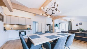 A modern kitchen with white cabinets, a wooden countertop, and a dining area with a large table and chairs.
