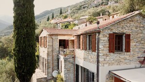 Un bâtiment en pierre avec des volets rouges, un balcon et une antenne parabolique.
