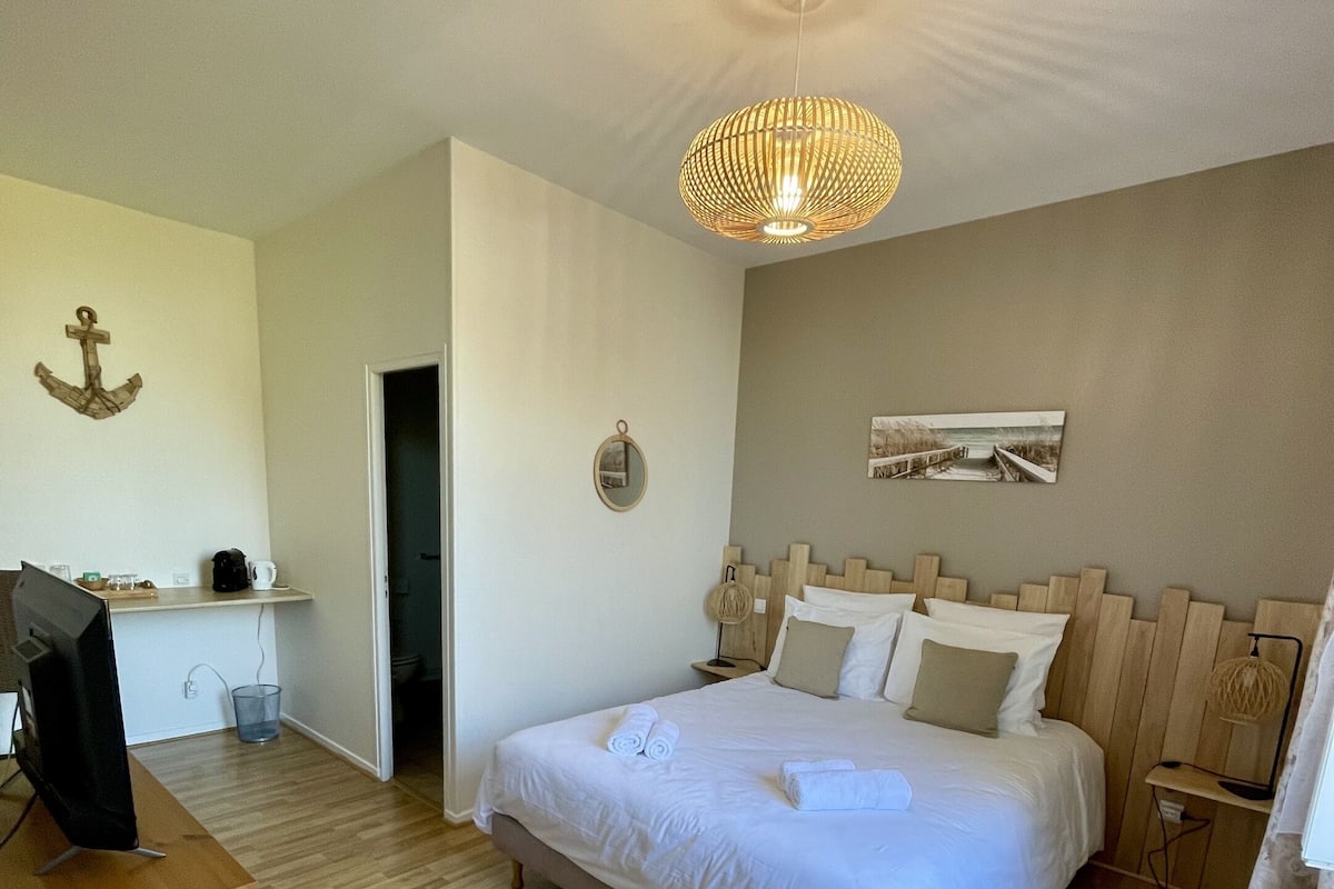 Une chambre à coucher avec un lit, un bureau, une télévision et un luminaire suspendu.