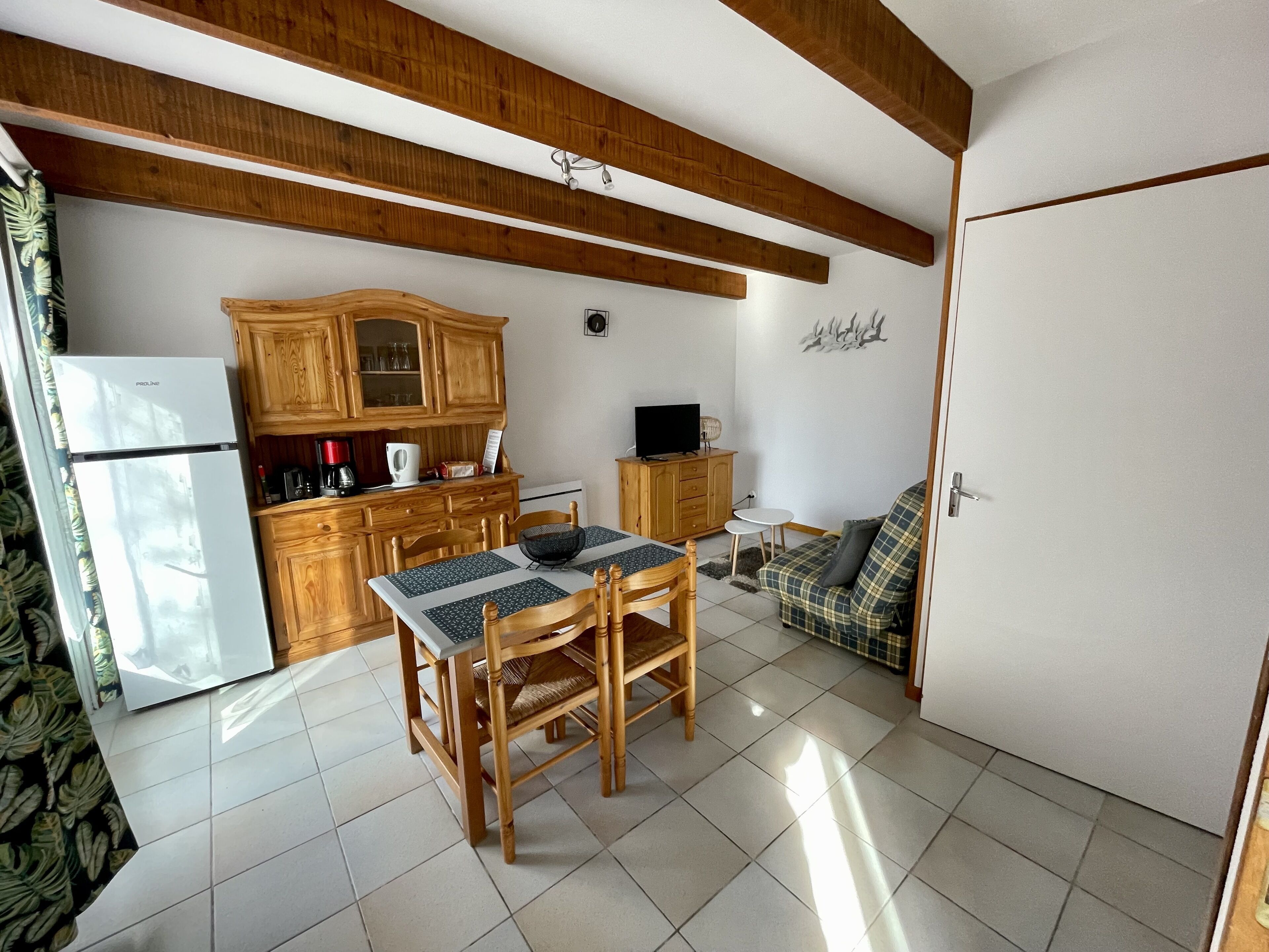 A compact kitchen with wooden cabinets, a dining table, and a sofa.