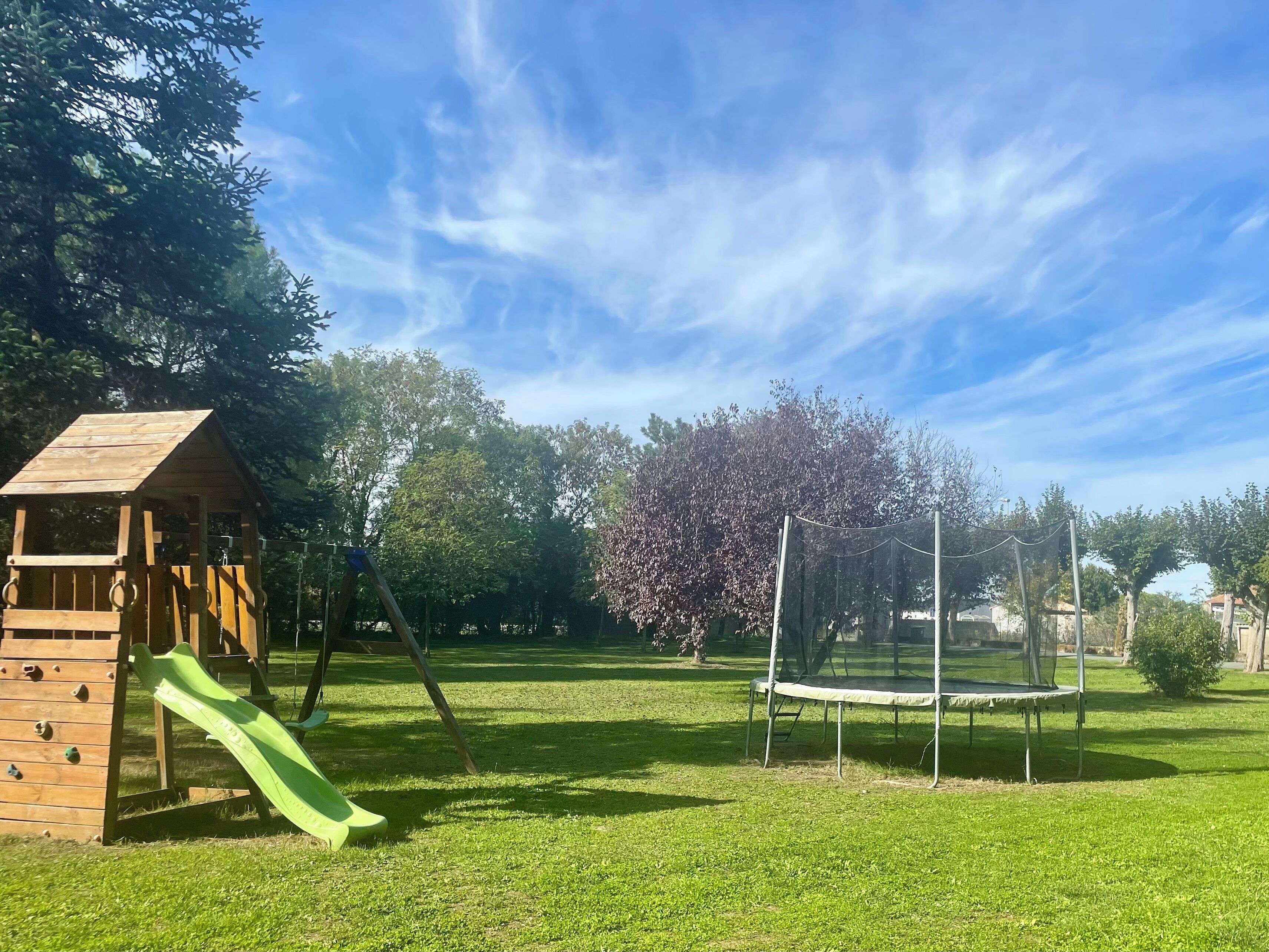 A playground with a slide, climbing wall, and trampoline.