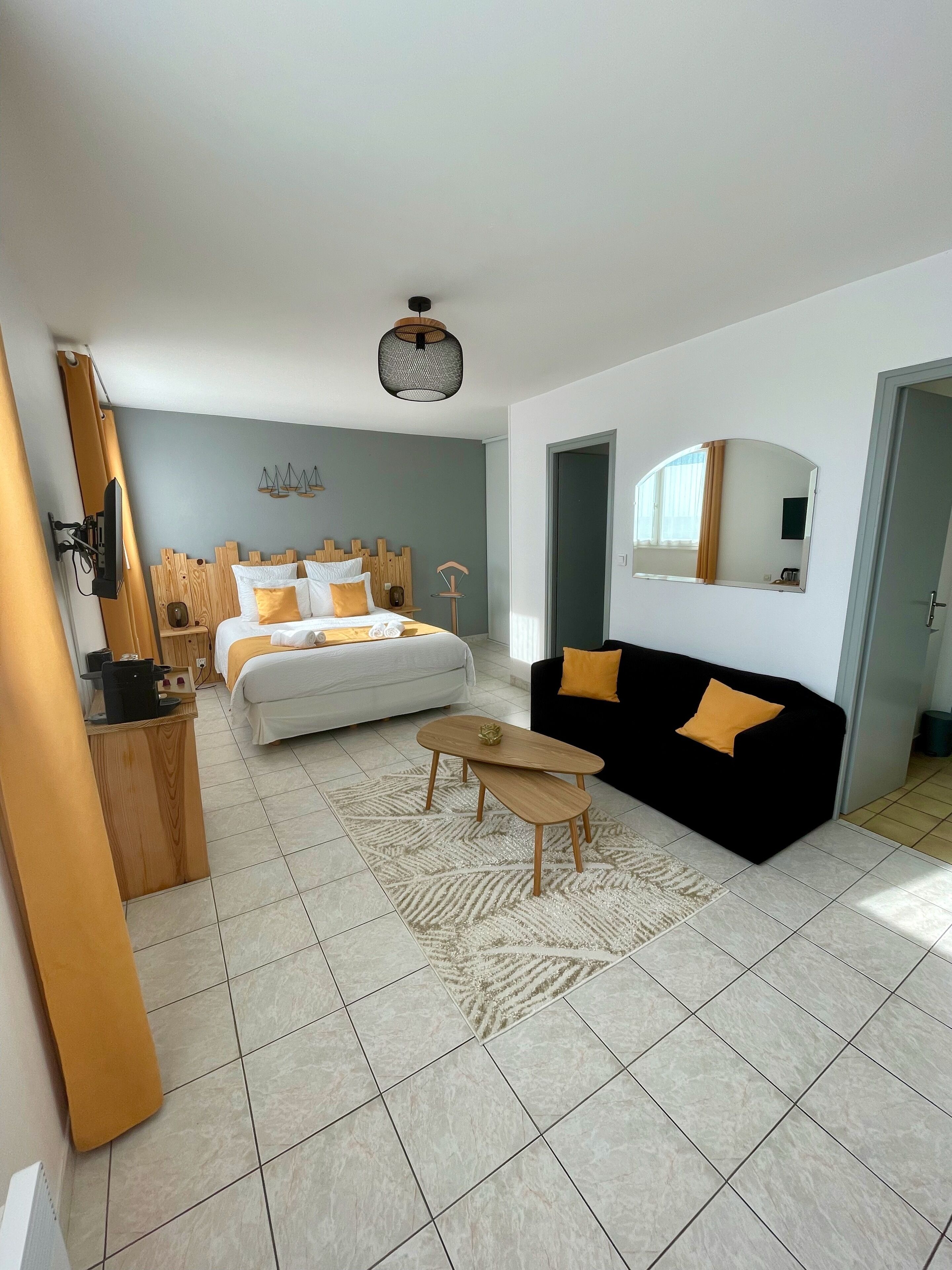Een moderne hotelkamer met een bed, een bank, een salontafel en een bureau met een computer.