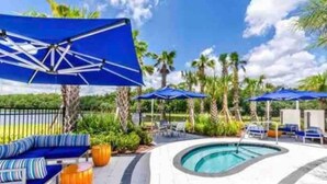 Un espace aménagé au bord de la piscine, avec des parasols bleus, des chaises longues et une piscine.