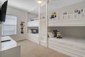 A child’s bedroom with bunk beds, a TV, and Minion-themed decorations.