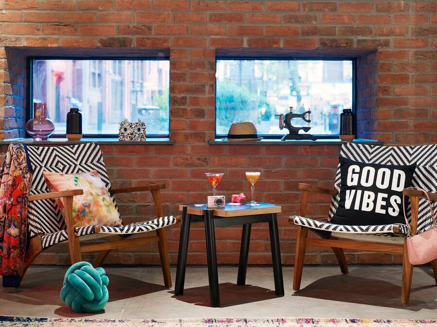 A cozy room with two wooden chairs, a small table, and a window with a view of a street.