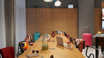 A modern conference room with a wooden table, laptops, and a foosball table.