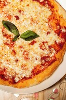 A pizza with cheese and basil on a white plate.
