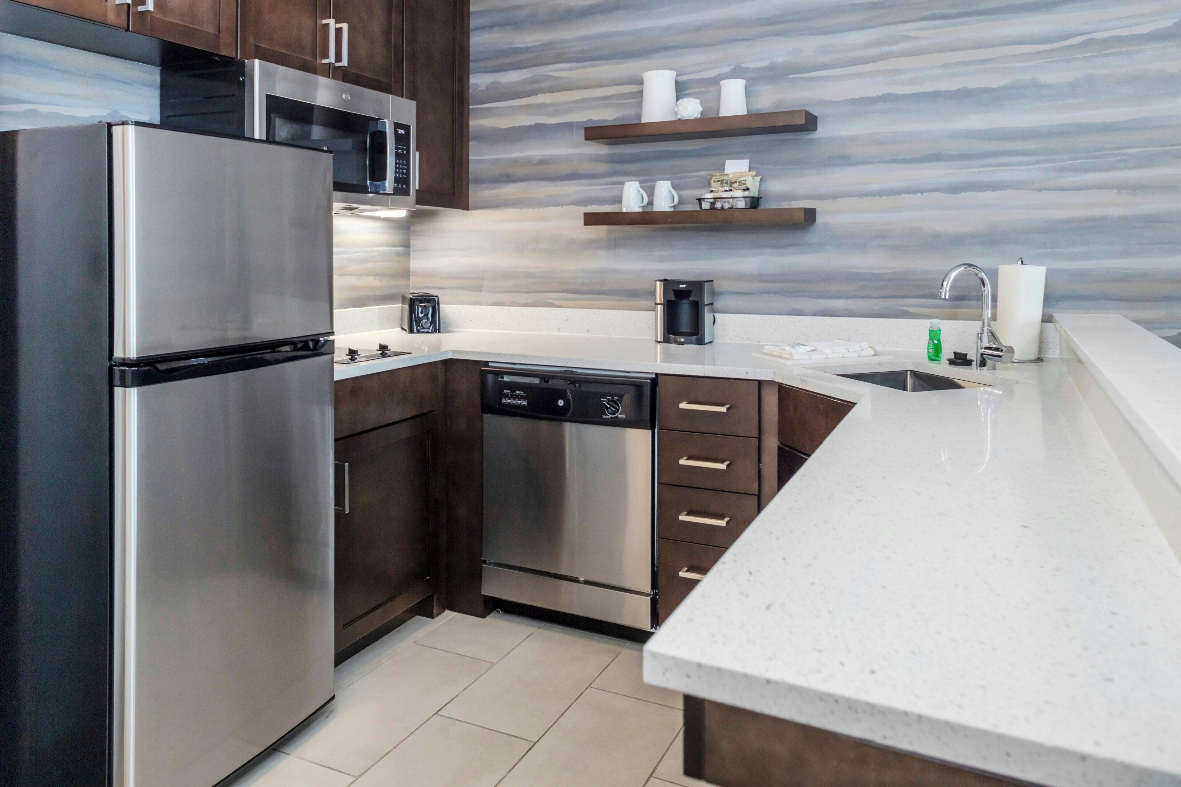A modern kitchen with stainless steel appliances, a dishwasher, and wooden cabinets.
