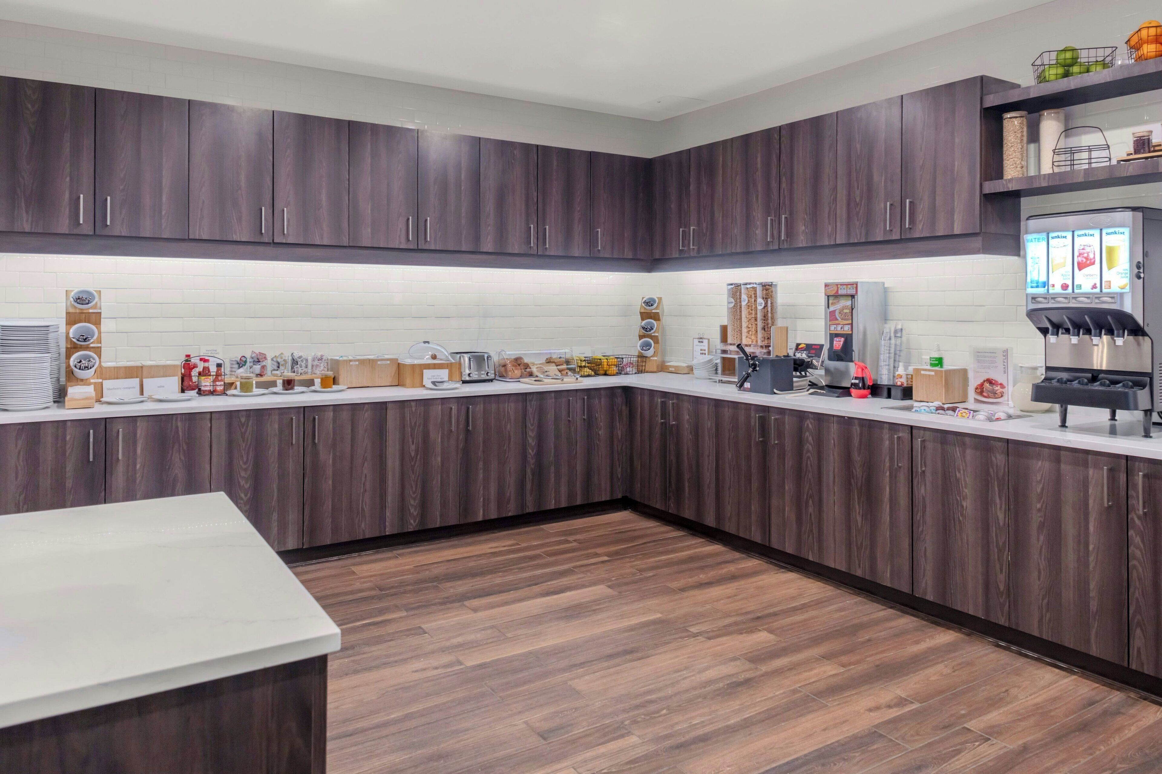A modern kitchen with dark wood cabinets, a white countertop, and a coffee machine.