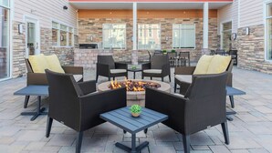An outdoor patio with wicker furniture, a fire pit, and stone walls. - Residence Inn by Marriott Detroit Sterling Heights (Clinton Township)