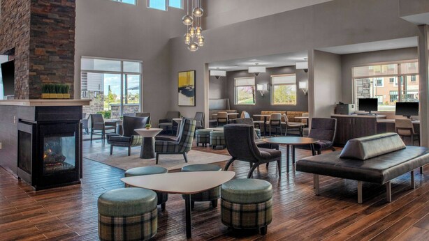 A spacious lounge area with multiple seating options, a fireplace, and large windows providing natural light. - Residence Inn by Marriott Detroit Sterling Heights (Clinton Township)