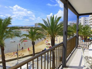 Ein Balkon mit Blick auf einen Strand, Palmen und einen klaren Himmel.
