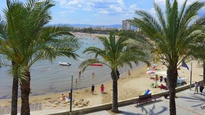 Een strand met palmbomen, een zandstrand en een boot in het water.
