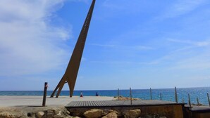 Een hoge, smalle monument op een strand met een heldere lucht.