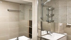 Een moderne badkamer met twee wastafels, een douchecabine van glas en een spiegel.