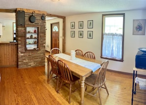A dining area with a wooden table, chairs, and a brick accent wall.