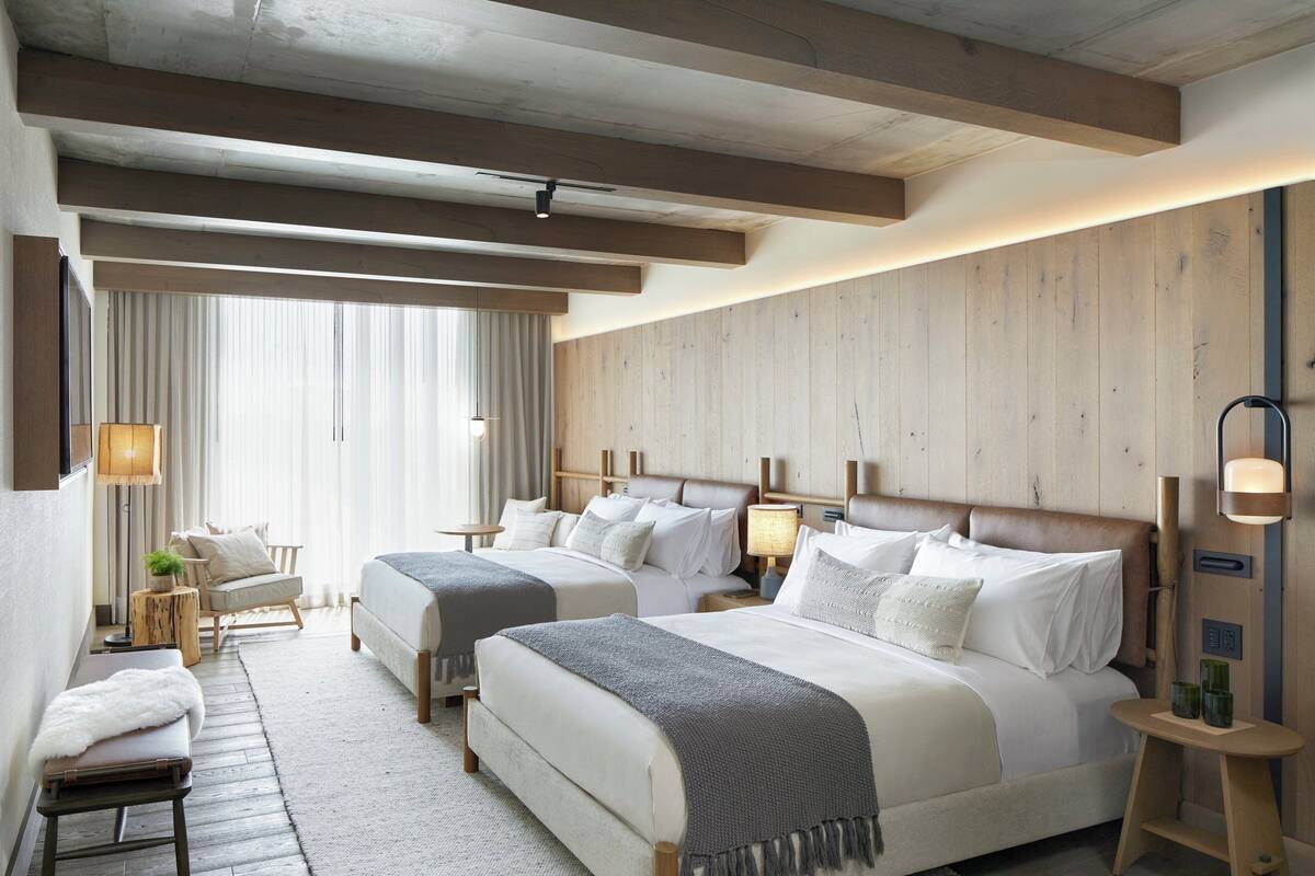 Ein Hotelzimmer mit zwei Betten, einer Sitzecke und Blick ins Freie.
