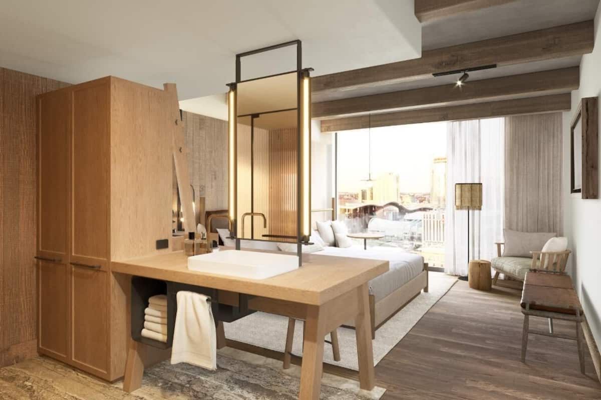 Ein modernes Schlafzimmer mit einem großen Bett, einem Holzschrank, einem Schreibtisch mit Spiegel und Blick auf die Stadt.