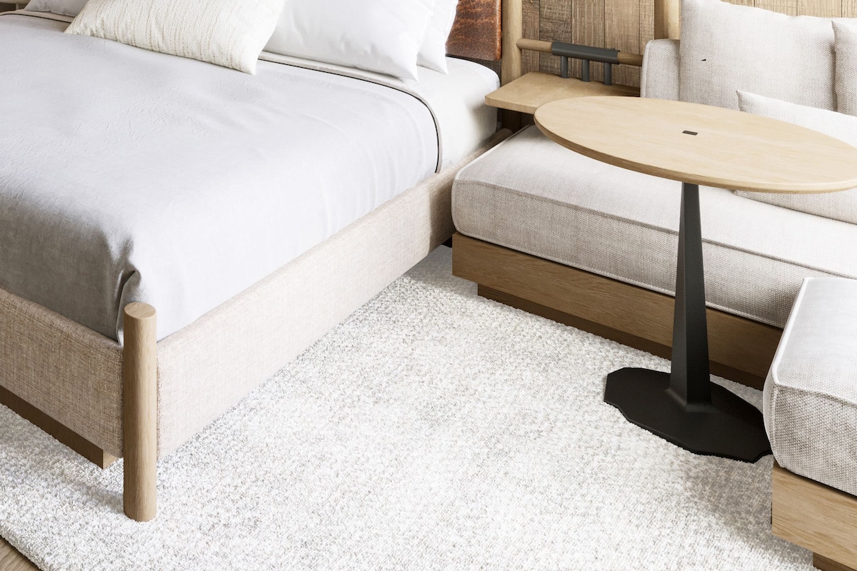 A modern bedroom with a wooden headboard, a round wooden table, and a sofa.