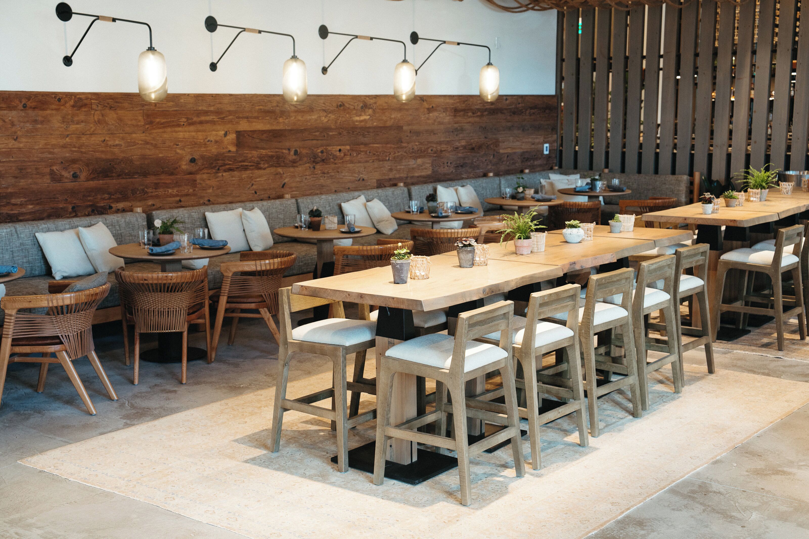 A restaurant with wooden tables and chairs, a brick wall, and hanging light fixtures.