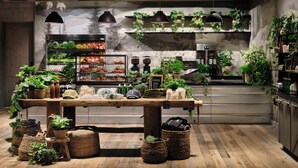 Een rustiek interieur met een houten tafel, hangplanten en een presentatie van fruit.