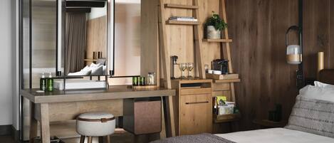 Een moderne slaapkamer met een bed, een houten bureau, een spiegel en een zithoekje.