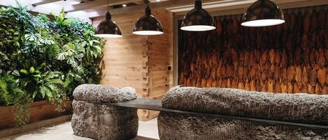Un interior moderno con un banco de piedra, vigas de techo de madera, lámparas colgantes y una pared con listones verticales de madera.