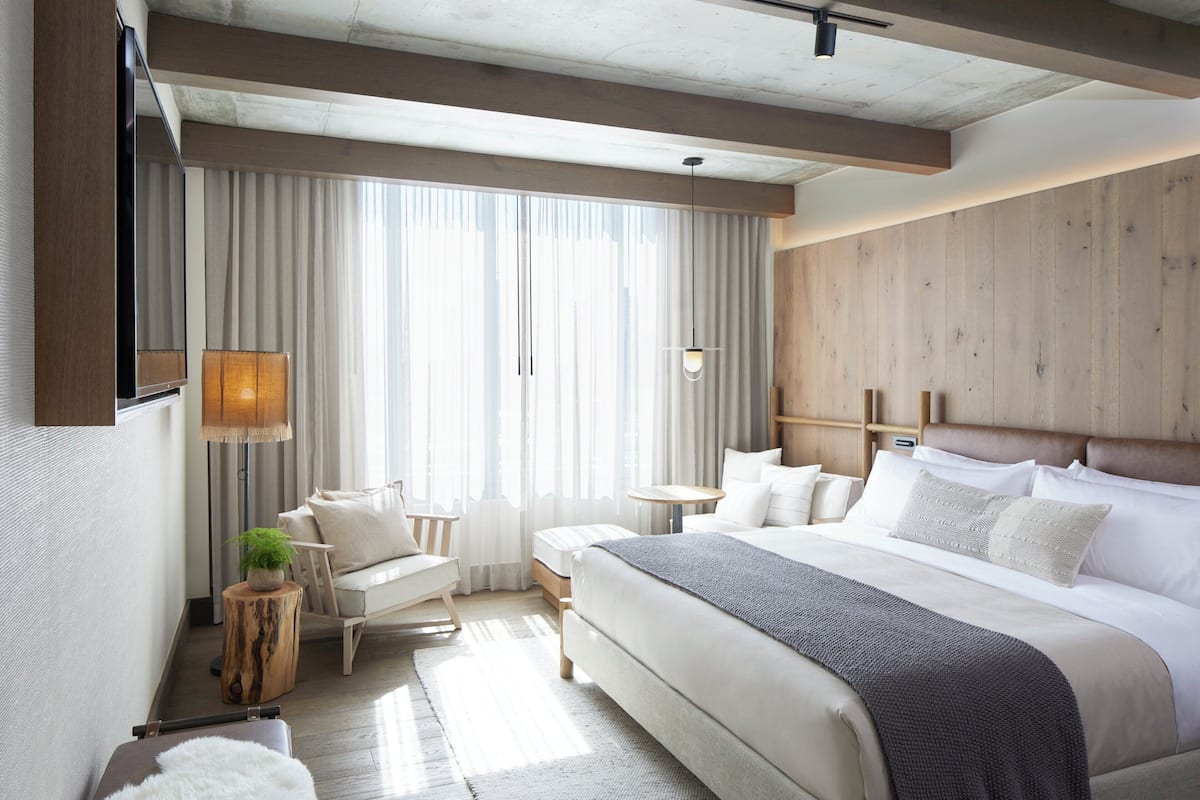 Ein modernes Hotelzimmer mit einem großen Bett, einem Schreibtisch, einem Stuhl und einem Fernseher.
