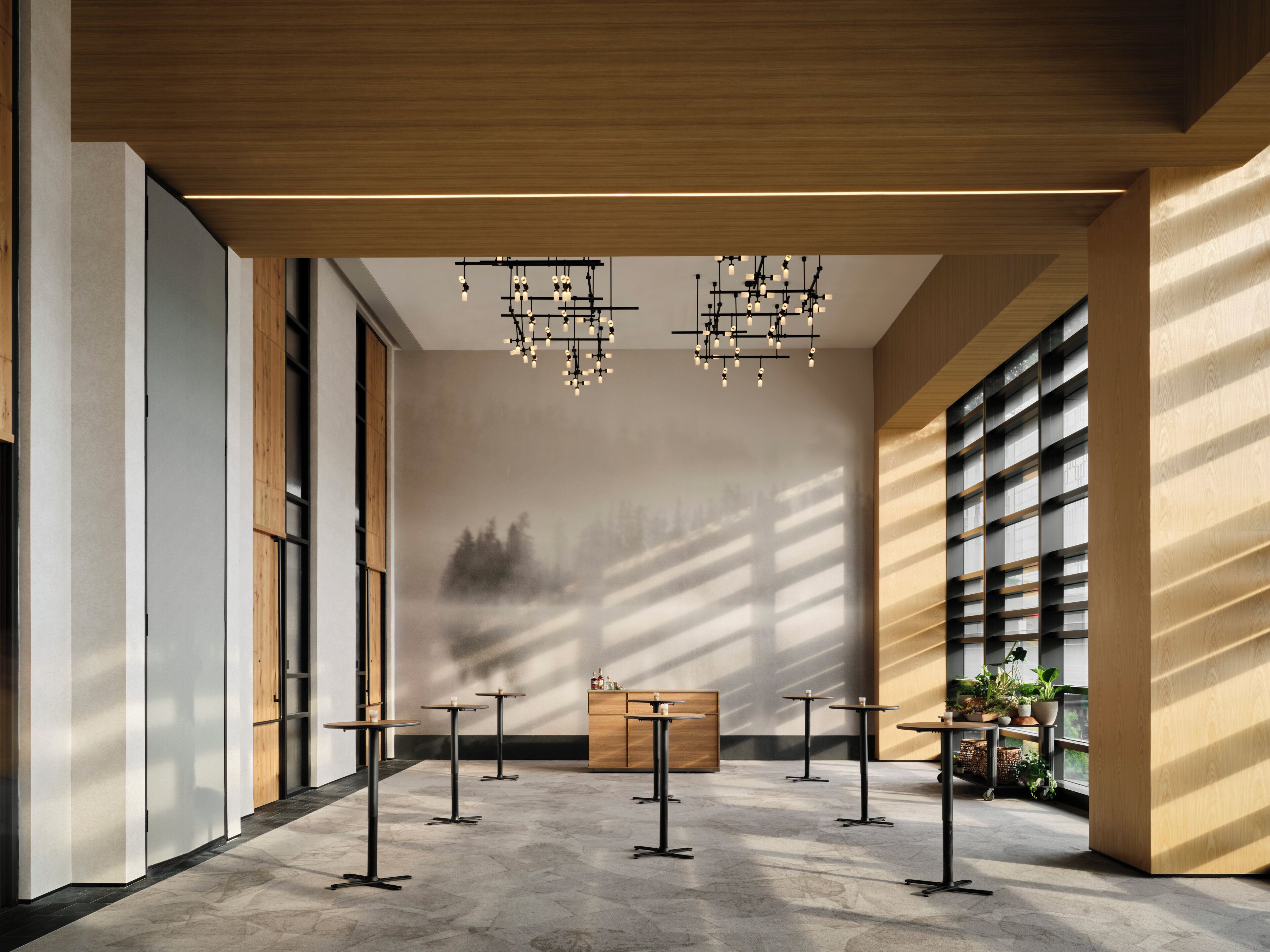 A modern interior with a high ceiling, multiple tables, and hanging lights.