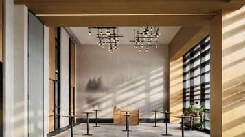 A modern interior with a high ceiling, multiple tables, and hanging lights.