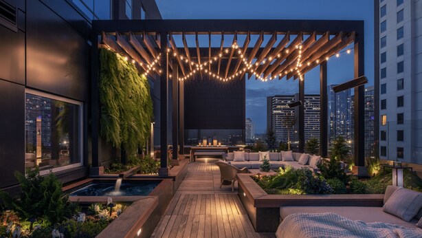 A rooftop terrace with a wooden deck, seating areas, a small water feature, and string lights. - 1 Hotel Nashville (Nashville)