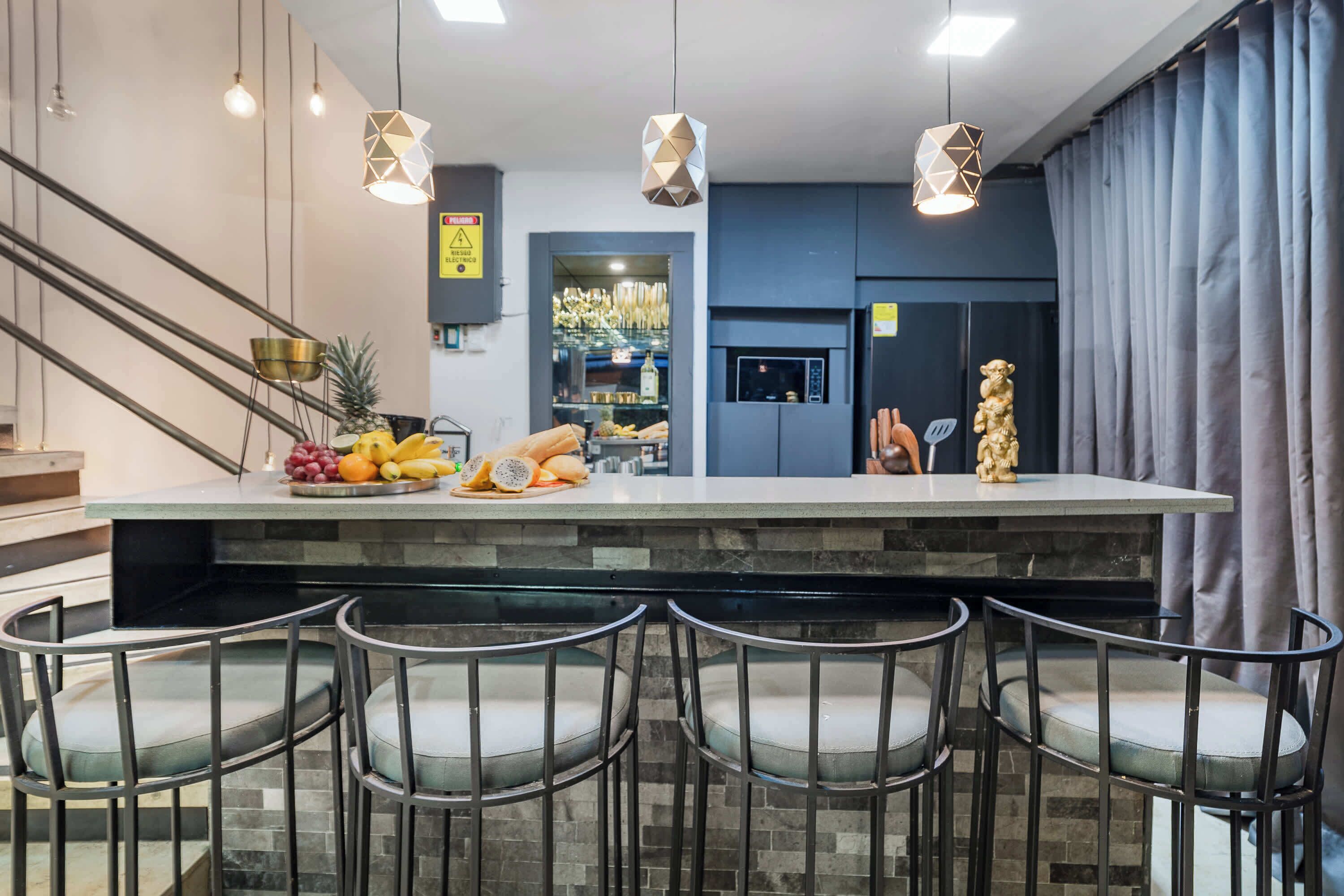 Een moderne keuken met een centraal eiland, barstoelen en hangende lampen.