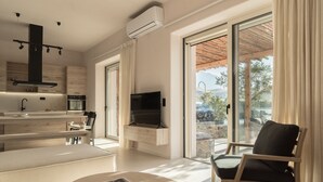 Ein modernes Wohnzimmer mit Flachbildfernseher, einer Couch, einem Essbereich und einem Balkon mit Blick ins Freie.