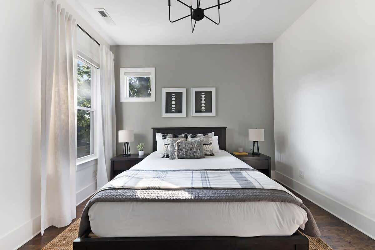 Una camera da letto con un letto, comodini, una finestra con tende e decorazioni alle pareti.