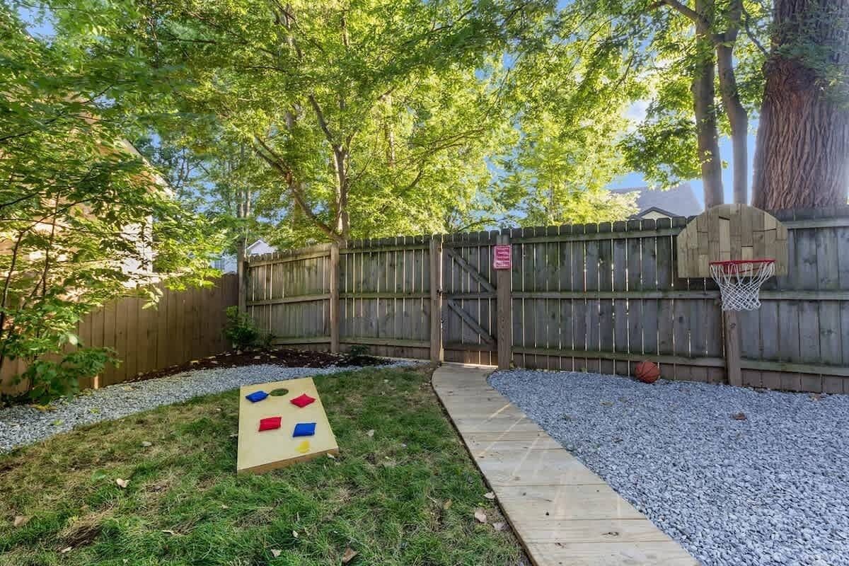 A backyard with a wooden fence, a basketball hoop, and a hopscotch game.