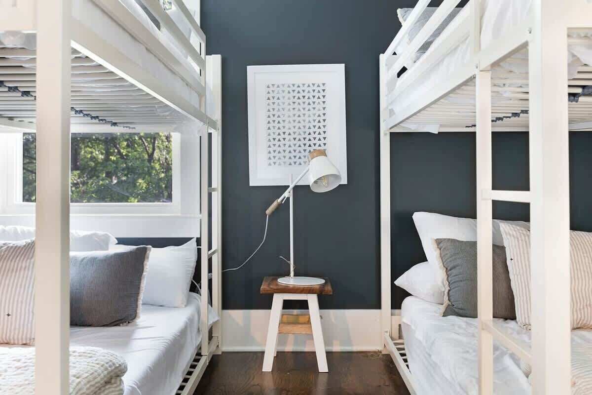 A room with bunk beds, a standing desk, and a framed artwork on the wall.