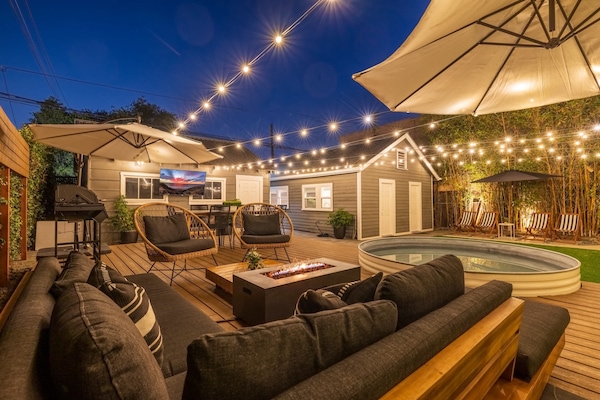 Large and lush private backyard with spacious 30 ft deck, resort lounge furniture, cantilever umbrellas, smart market lights, outdoor smart tv, firepit, and heated pool/hot tub.