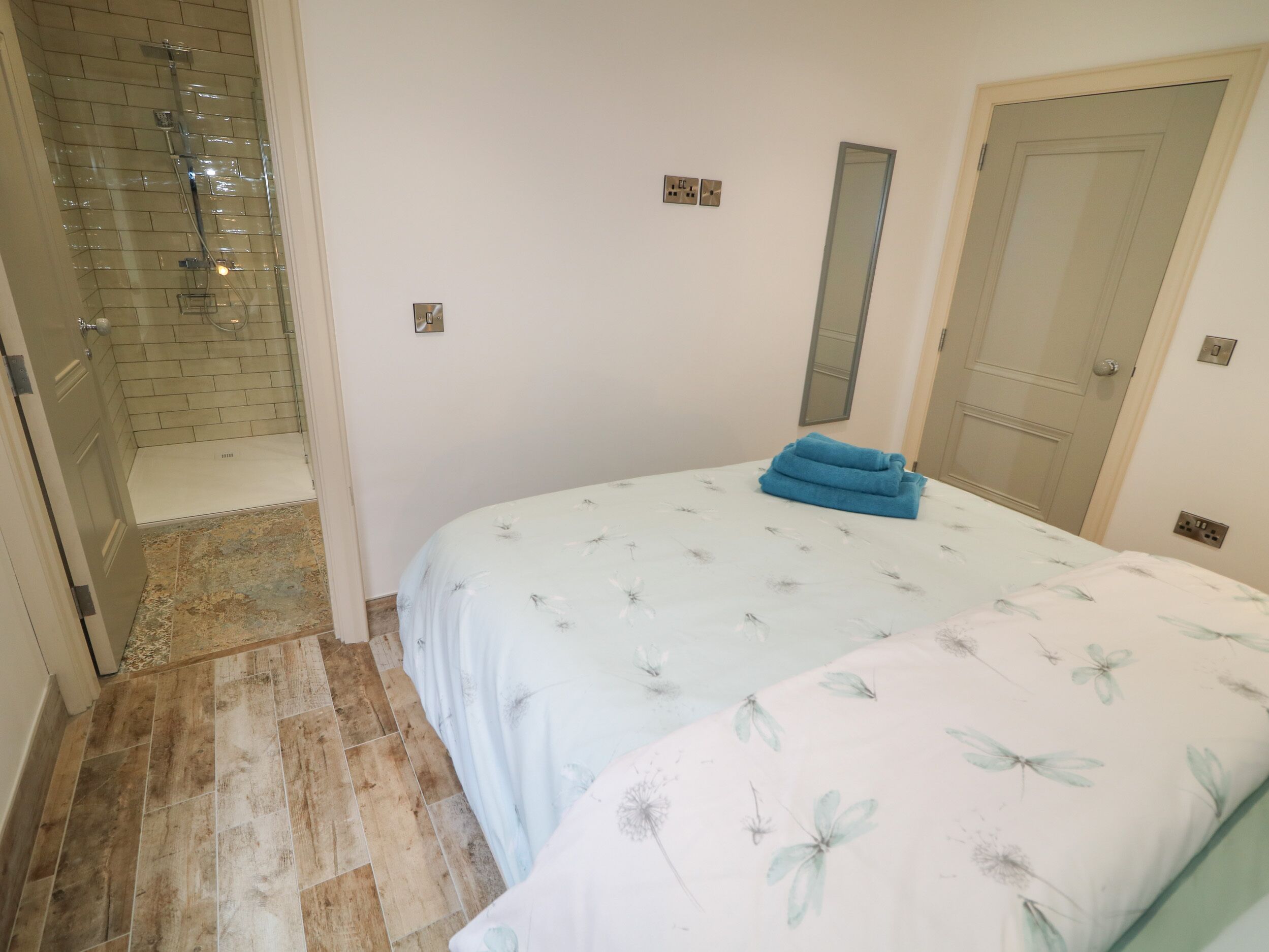 A bedroom with a bed, a shower, and a door.