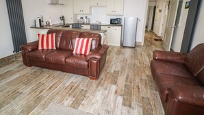 Un apartamento moderno con un sofá de cuero marrón, una zona de cocina y una mesa de comedor.