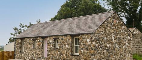 A small stone building with a sloped roof, a single door, and a window.