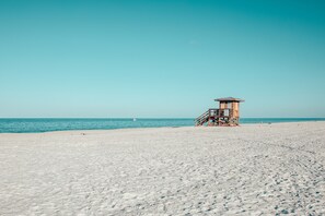 A lifeguard tower on a sandy beach with clear blue water in the background. - Island Vibes + Modern Comfort at Lido Beach! (Sarasota)