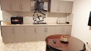 A compact kitchen with a microwave, a sink, and a decorative clock. - Captivating 1-bed Apartment Fully Furnished (Lahore)
