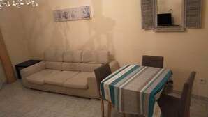A living room with a beige sofa, a small table with a striped tablecloth, and a dark-colored armchair. - House of roae (Terni)