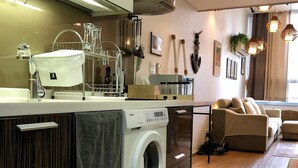 Eine moderne Küche mit integriertem Waschmaschine, Holzschränken und einem Essbereich mit einer Couch und einem Tisch.